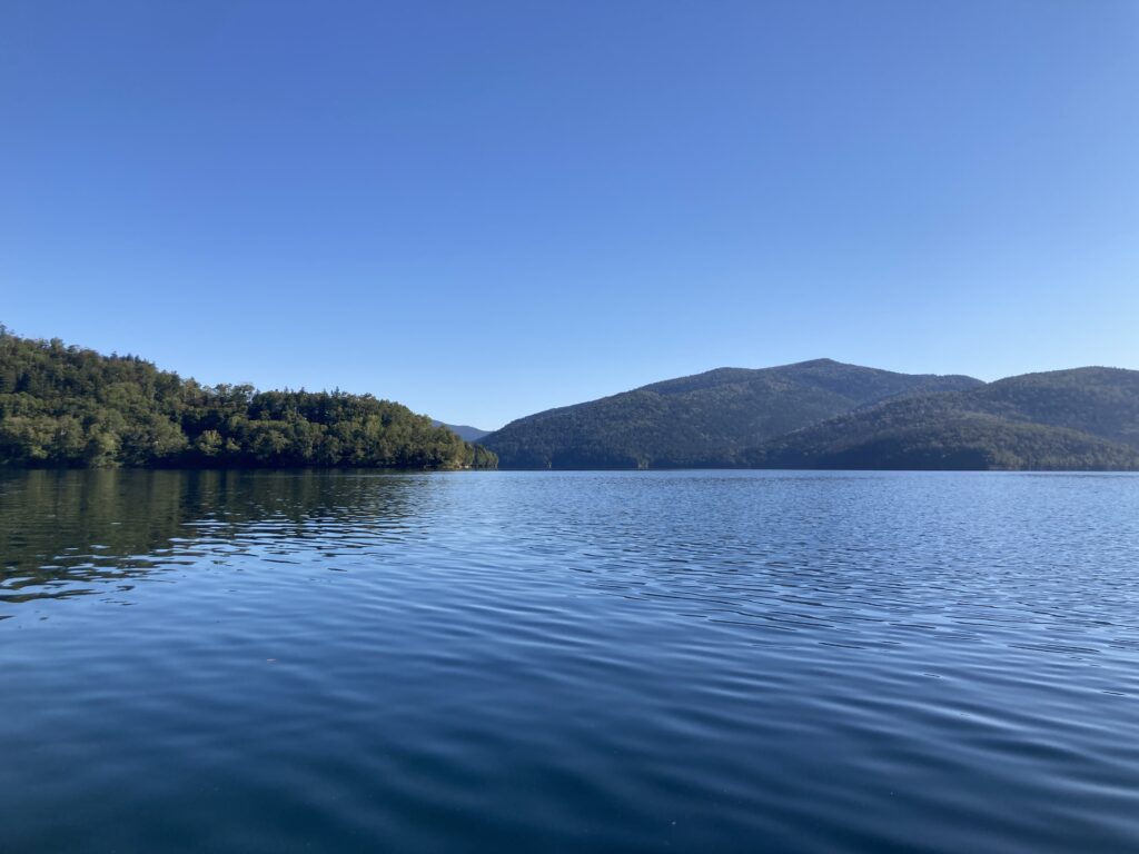ボートの上から取った湖とその周りの山々を移した写真